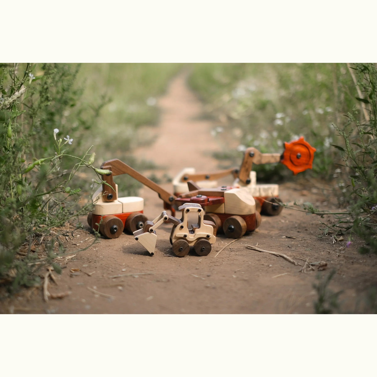 Maple Digger in pale maple and walnut displayed outdoors on a dirt path with wildflowers and wooden construction vehicle