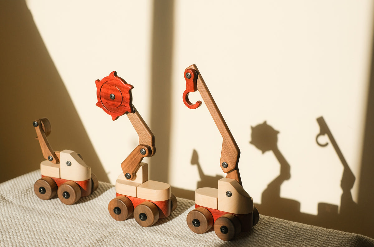 Excavator, trench digger and crane from the set on a textured throw, casting long shadows on a sunlit wall