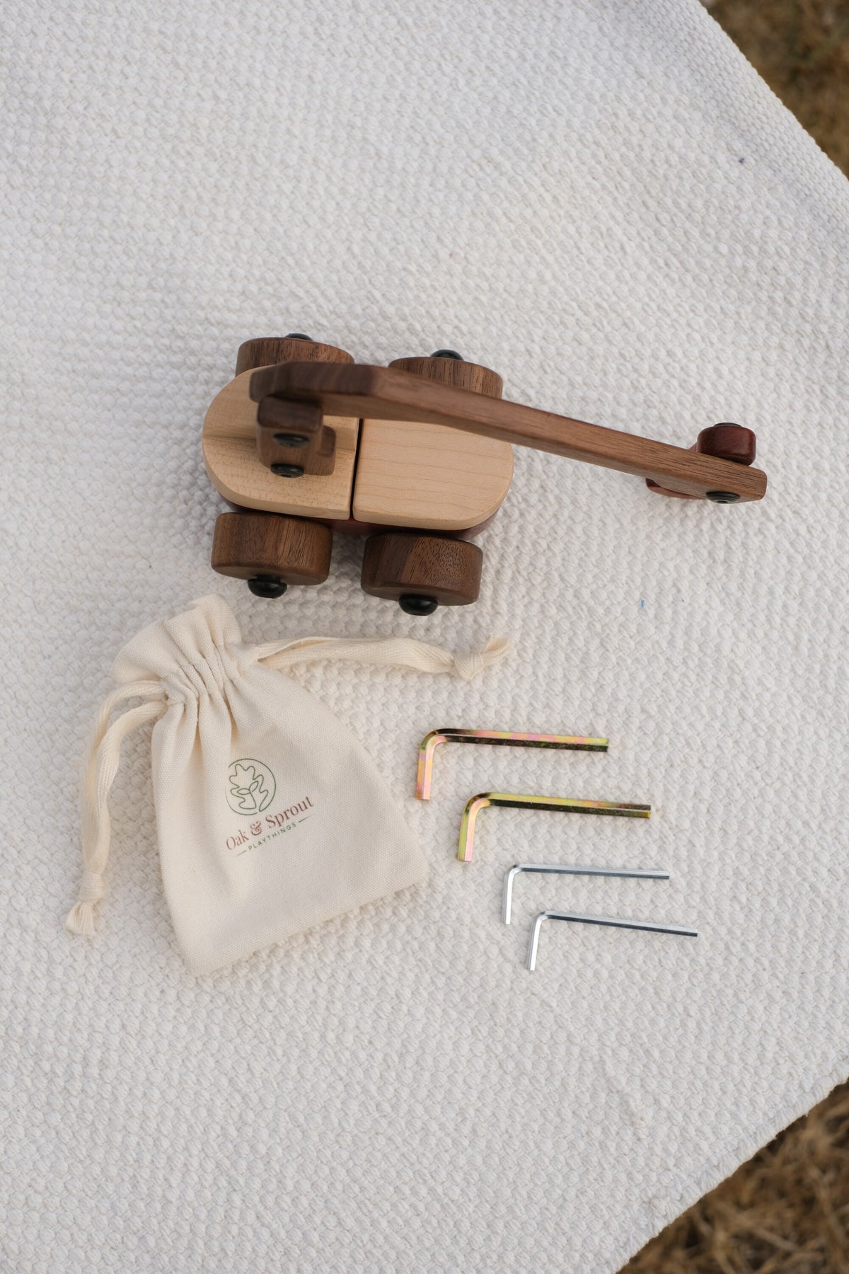 Walnut & Maple Crane from above with an Oak & Sprout cotton drawstring pouch and four child-size Allen keys on a white textured throw