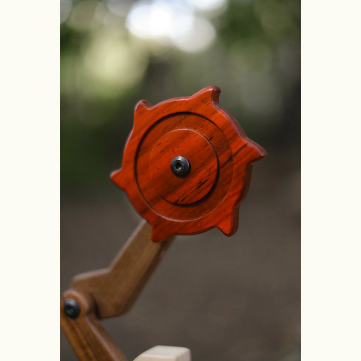 Padauk & Maple Trench Digger spinning cutter wheel close-up, deep coral-red padauk with maple arm and walnut joint