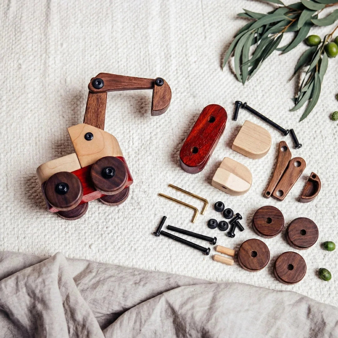 Maple Padauk Walnut Excavator kit partially assembled with components laid flat, showing coral padauk, pale maple, and dark w