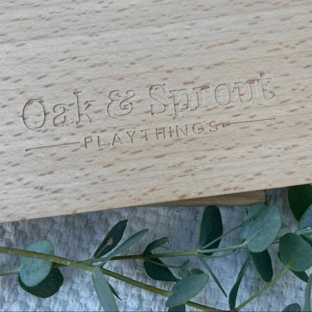 Oak & Sprout lowercase alphabet puzzle board reverse, pale mahogany with laser-engraved brand logo on linen mat