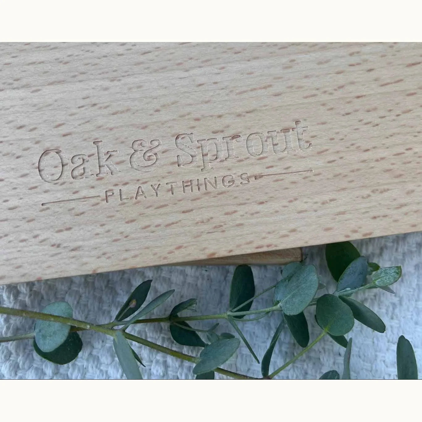 Sky Bloom puzzle beech wood frame back showing laser-engraved Oak & Sprout Playthings logo on white knitted playmat