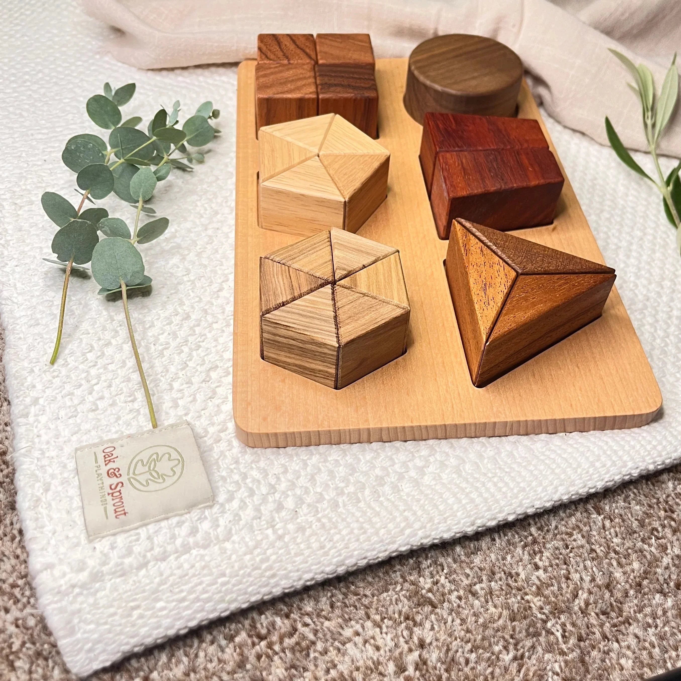 Oak & Sprout shape-sorting puzzle fully assembled on branded playmat, showing walnut, padauk, maple and zebrano pieces