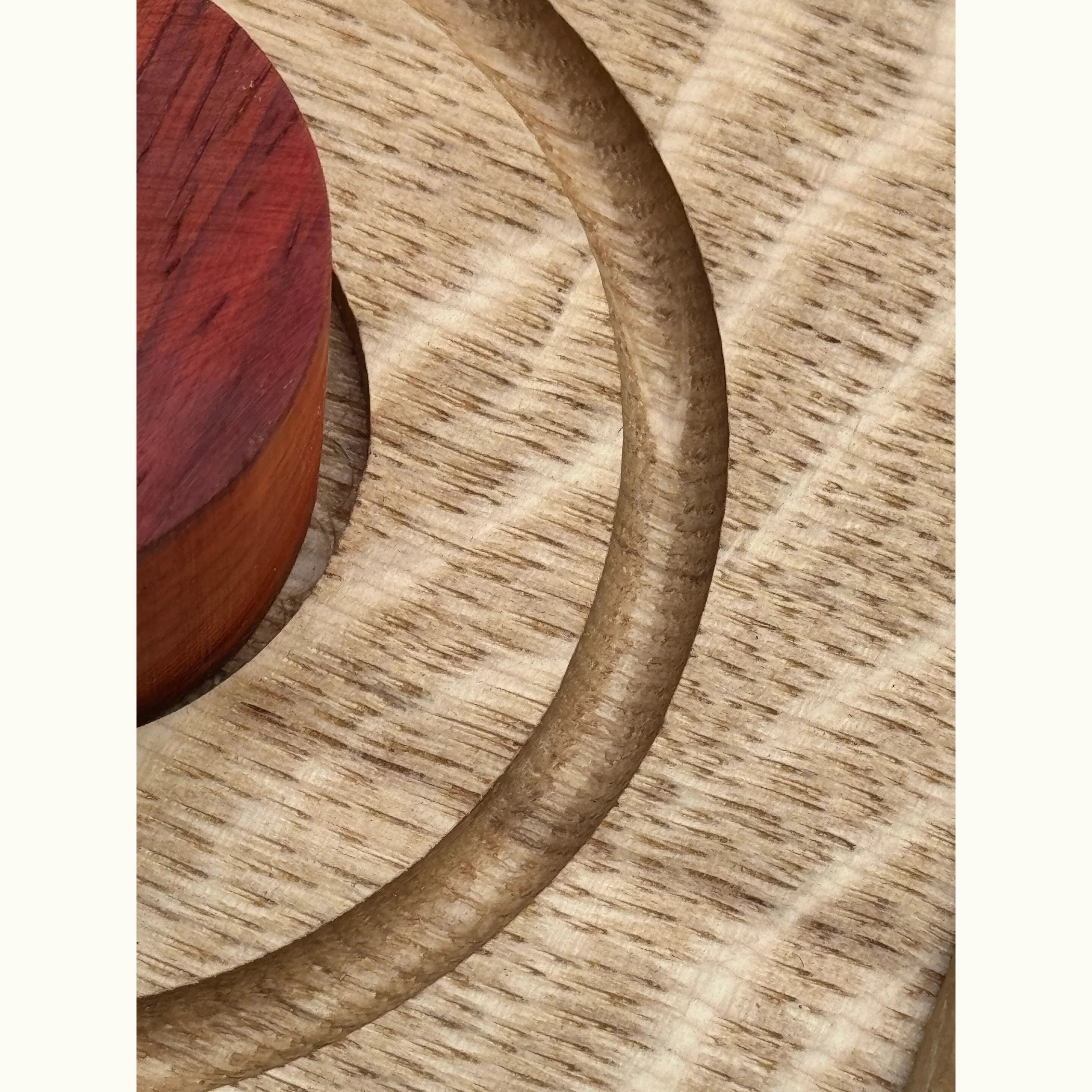 Trace & Place oak board close-up showing routed tracing channel with coral-red Padauk peg, highlighting precision handcraftin