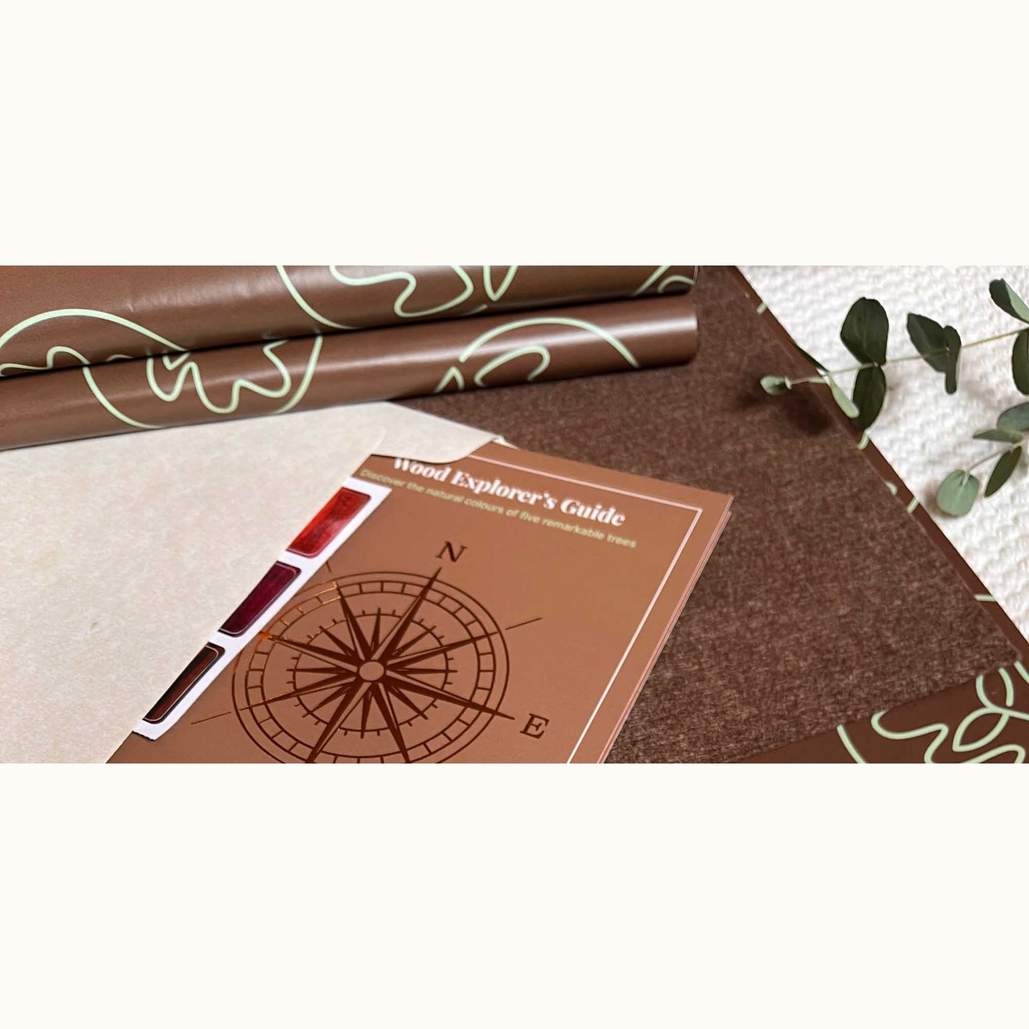 Alphabet Tracing Board gift packaging: botanical-printed wrap, felt sheet, and Wood Explorer's Guide booklet with wood sample