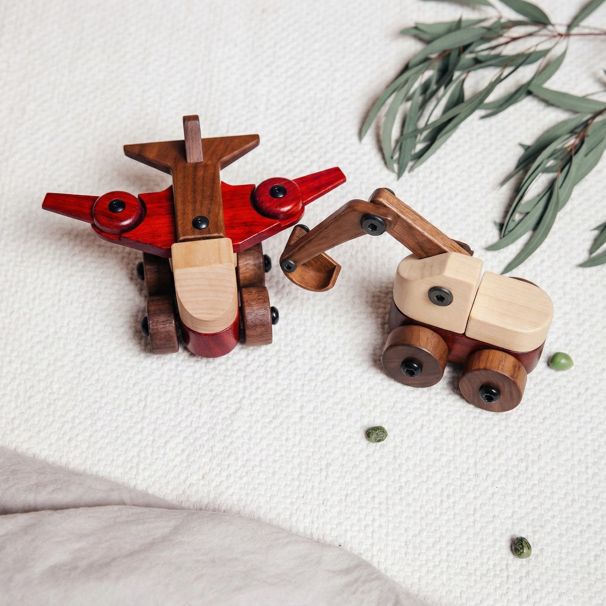 Aeroplane & Excavator Bundle flat-lay overhead view on waffle playmat; excavator shows maple, walnut, and padauk hubs