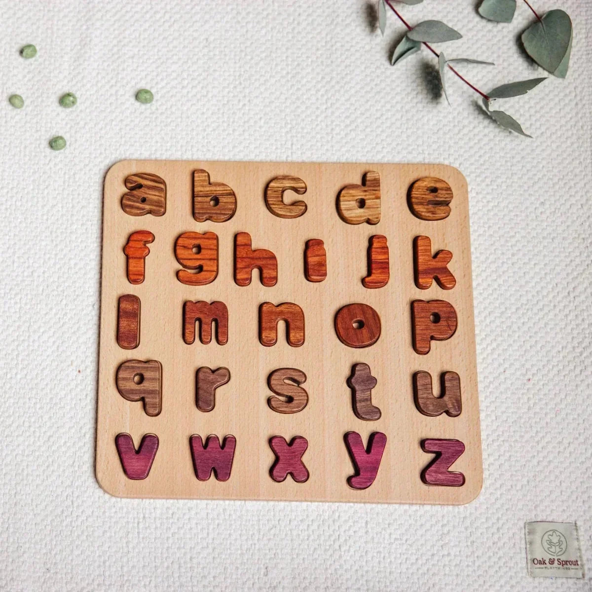 Early Learning Bundle lowercase alphabet puzzle assembled flat-lay, letters in tigerwood, mahogany, walnut, zebrano and