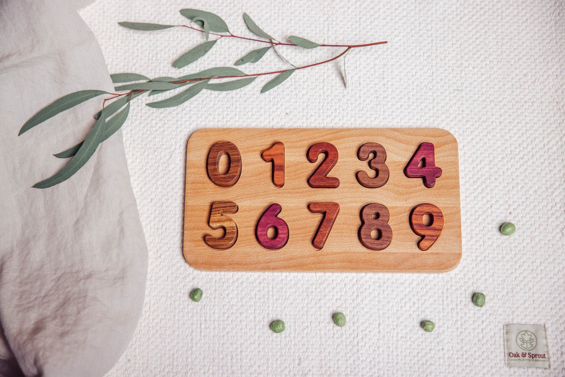 Wooden number puzzle on a textured surface with green leaves.