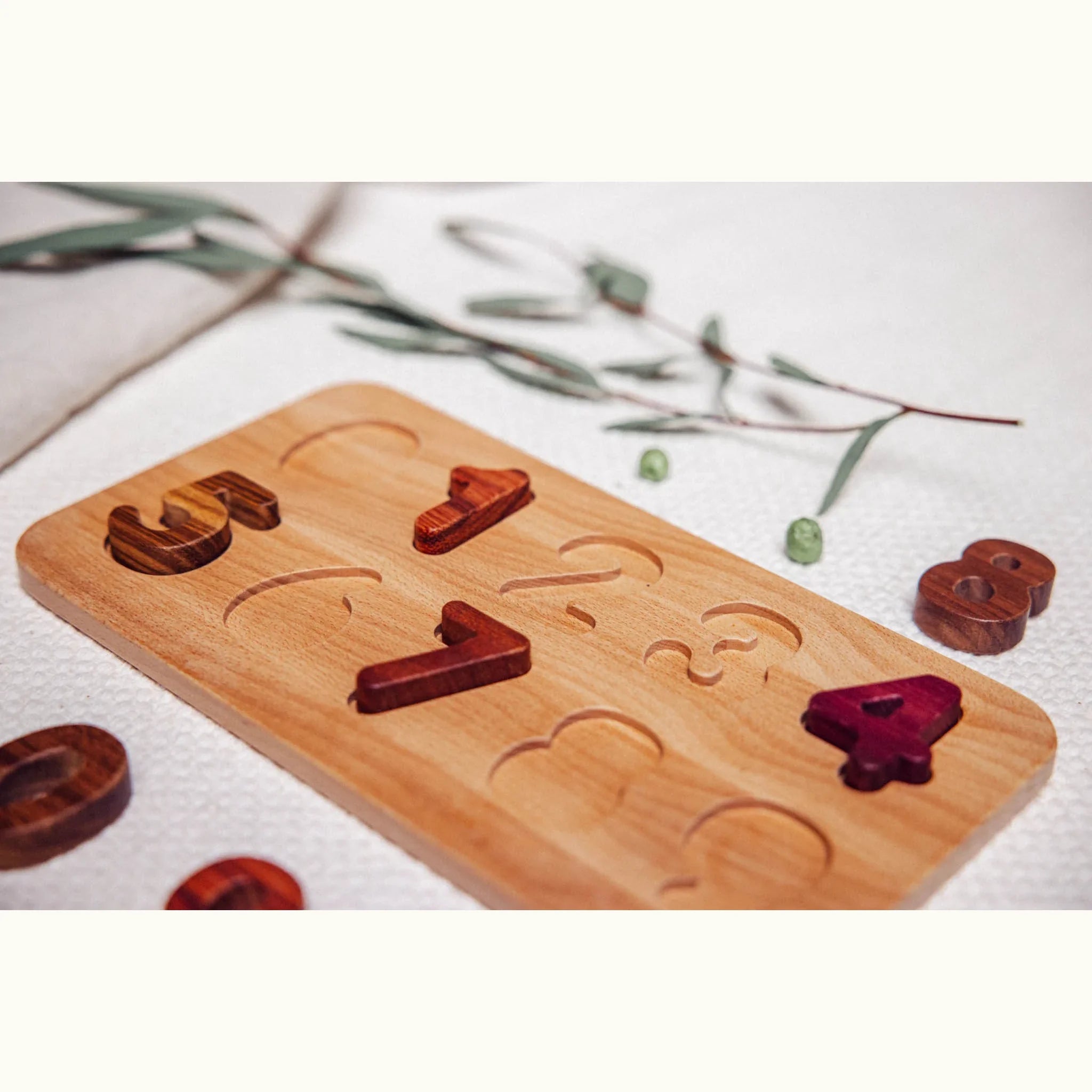 Oak & Sprout number puzzle board partially assembled, showing Zebrano, Purpleheart and Walnut digit pieces on linen playmat