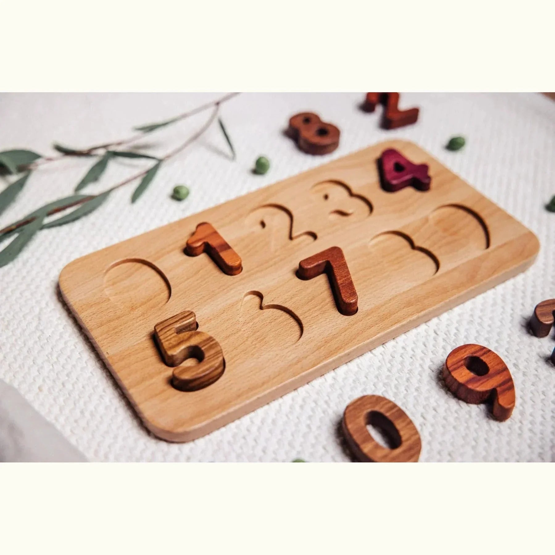 Oak & Sprout number puzzle partially assembled, Tigerwood, Walnut, Purpleheart and Mahogany pieces scattered on white muslin