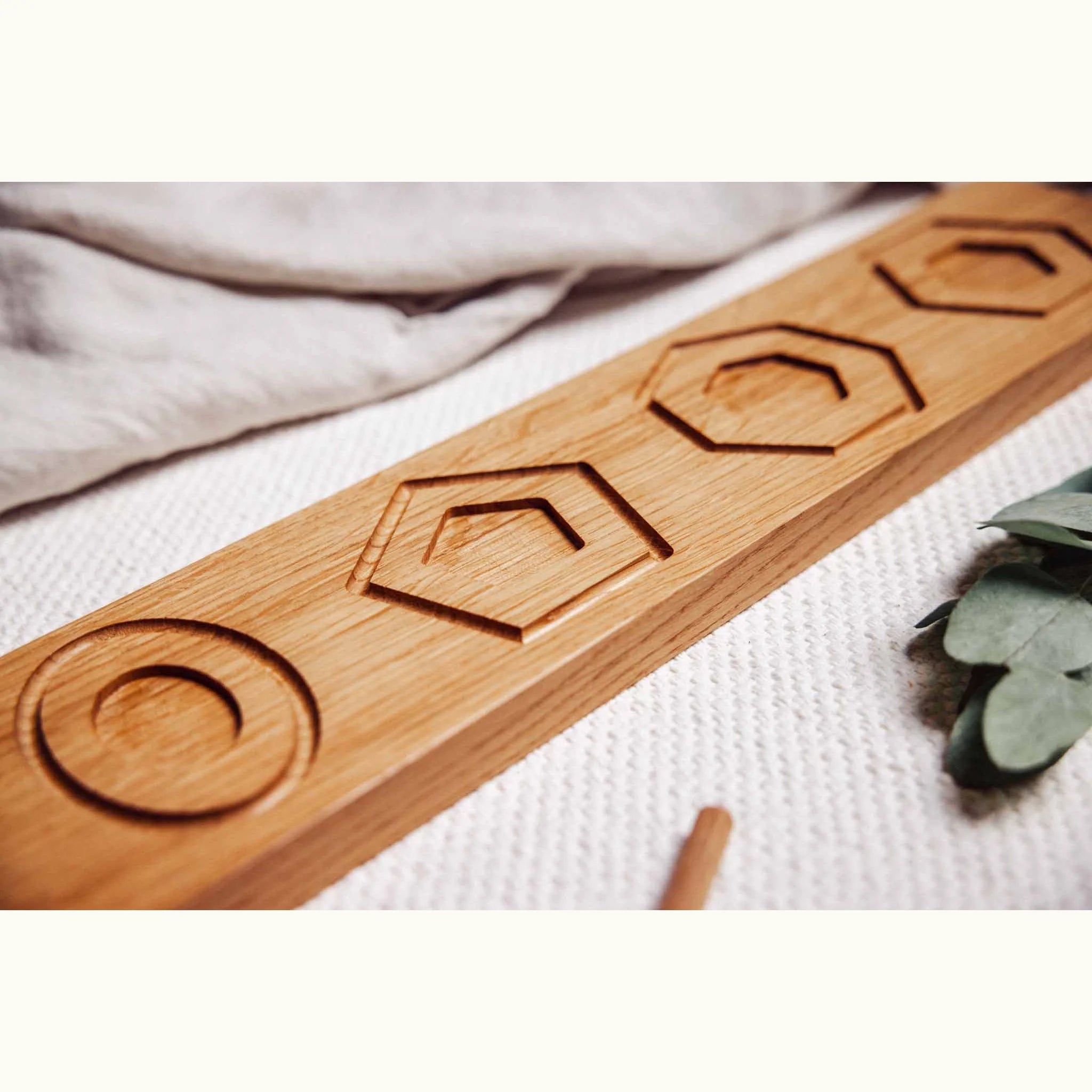 Trace & Place oak board showing engraved concentric circles, pentagons and hexagons, angled on a white textured playmat