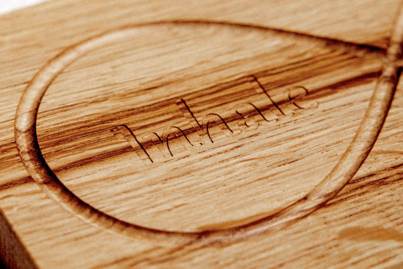 Infinity Breathing Board oak surface close-up showing laser-engraved inhale text and finger-trace infinity loop groove