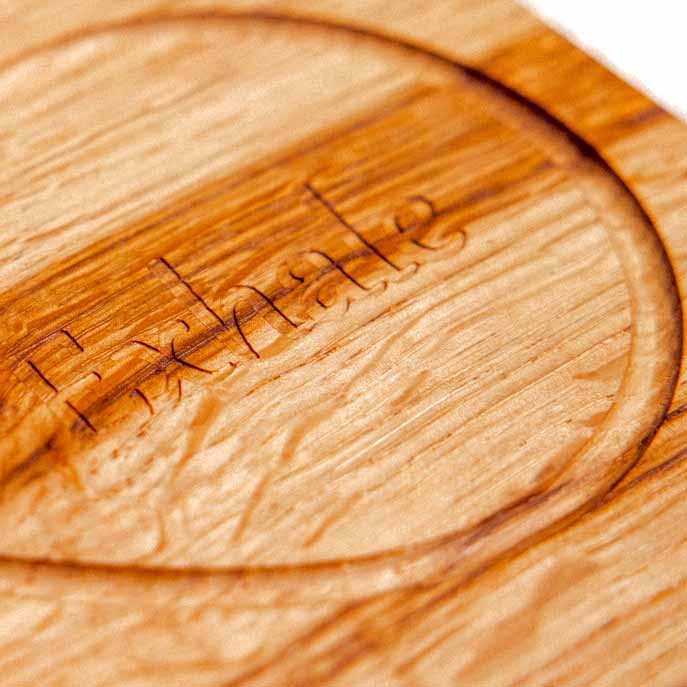 Infinity Breathing Board oak underside showing hand-engraved brand mark within recessed circular groove, natural grain detail