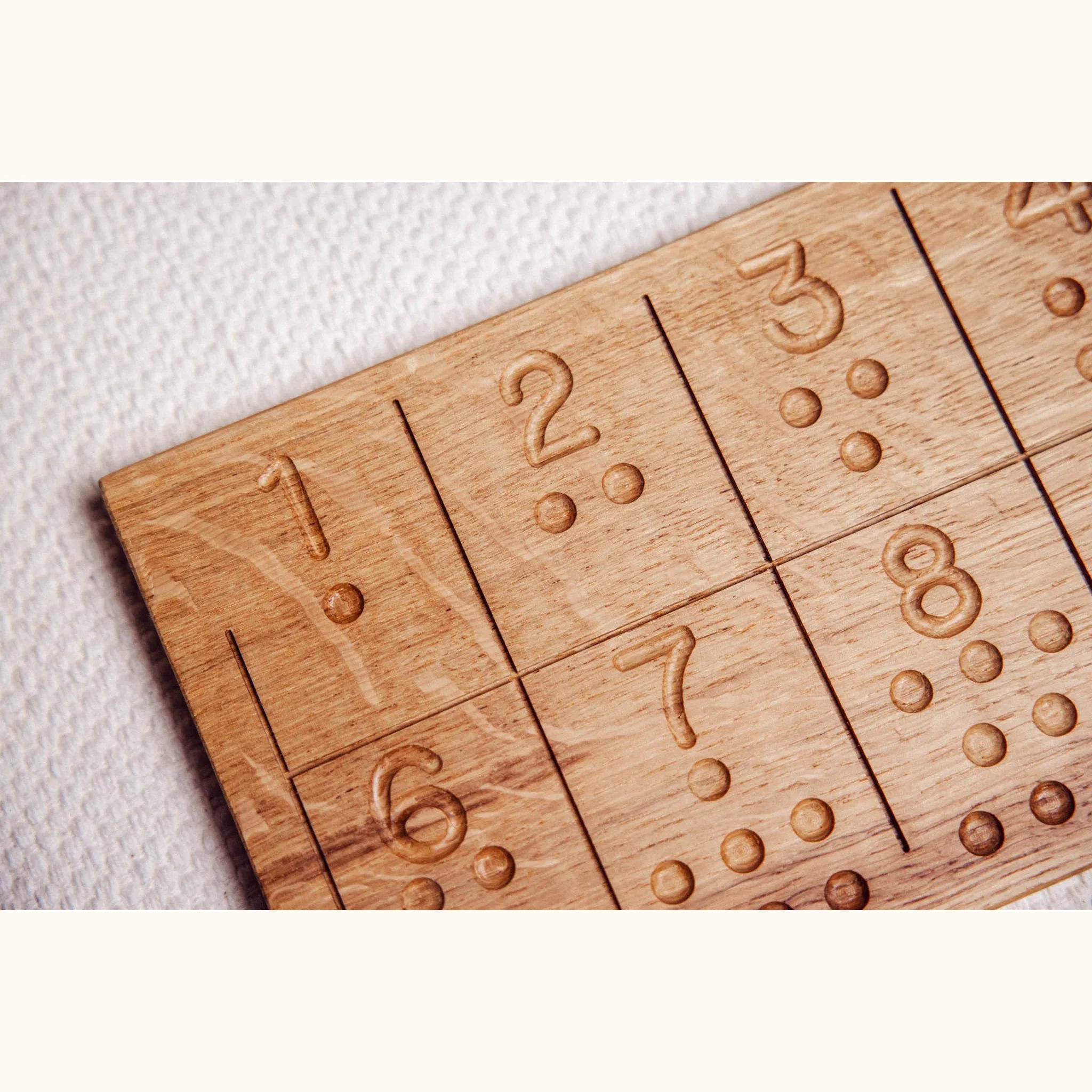 Numbers Tracing & Balls oak board close-up showing carved numerals 1–8 with counting dot indentations, warm honey grain visib