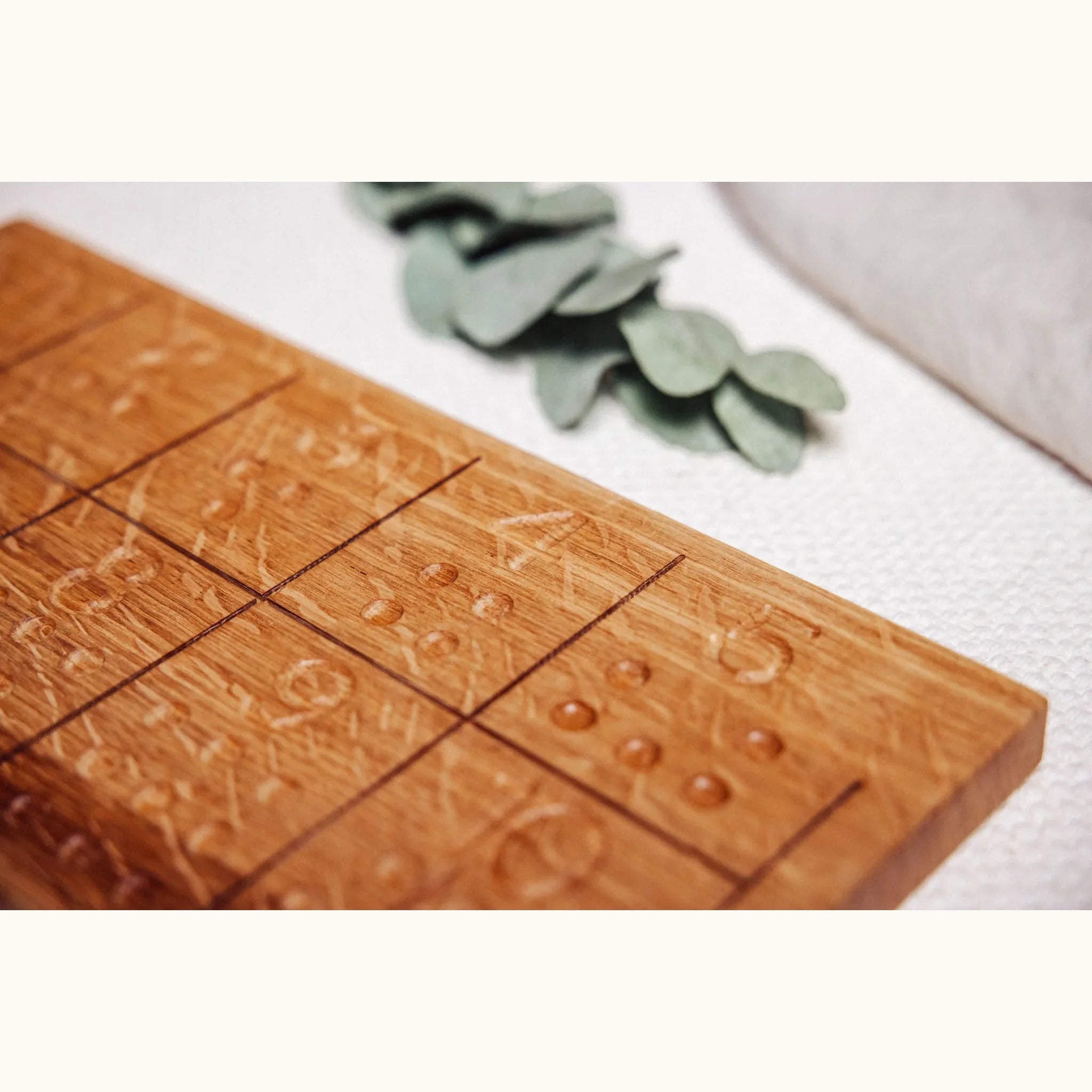 Close-up of Numbers Tracing & Balls oak board showing carved number grooves and raised ball dots with warm honey grain detail