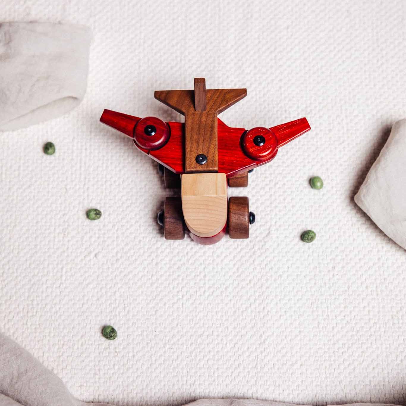 Walnut & Padauk Aeroplane seen from above on cream playmat, showing padauk wings, walnut fuselage and maple nose cone