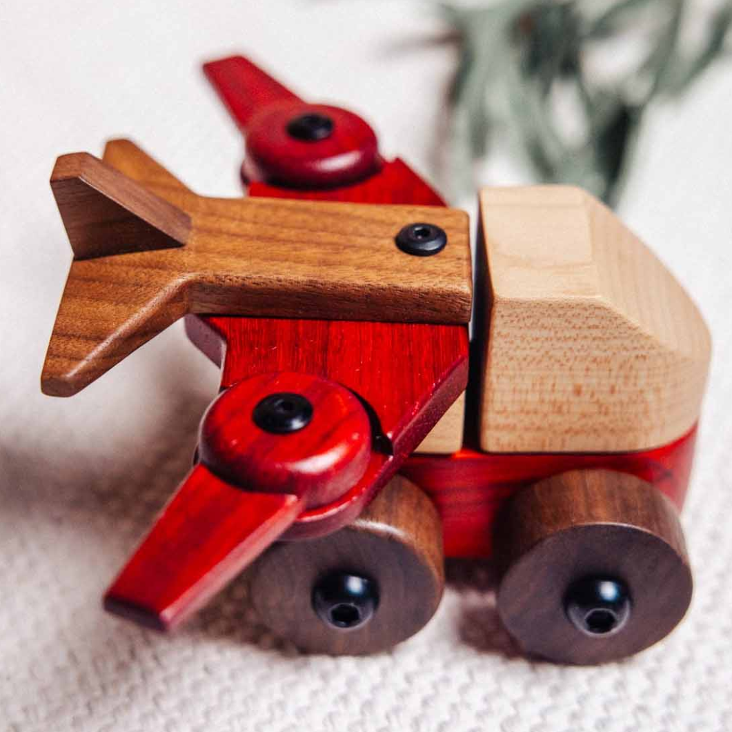 Wooden toy airplane with walnut and padauk wood on an oak and sprout playmat