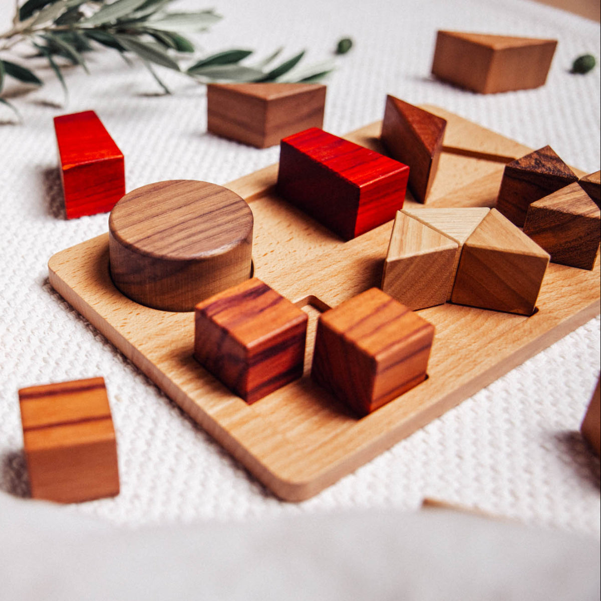 Wooden geometric shapes on a wooden board with a white fabric background