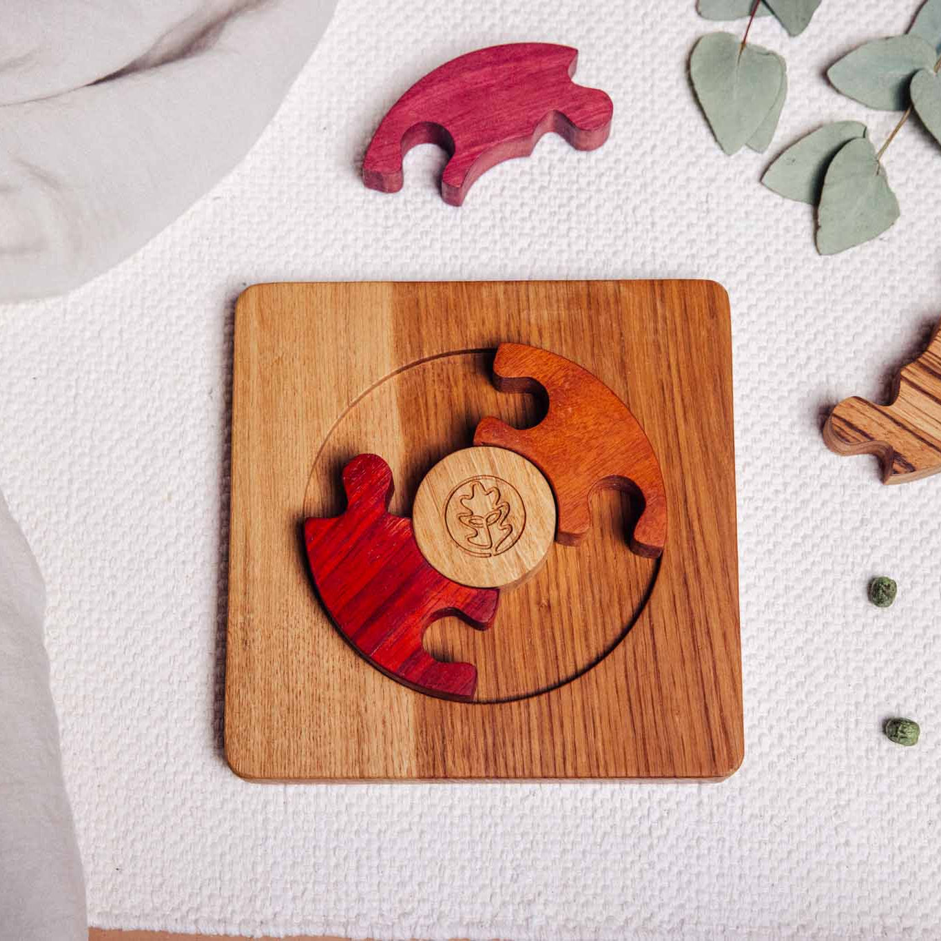 Unity Puzzle partially assembled: padauk and zebrano pieces removed beside oak base, tigerwood and padauk segments fitted ins