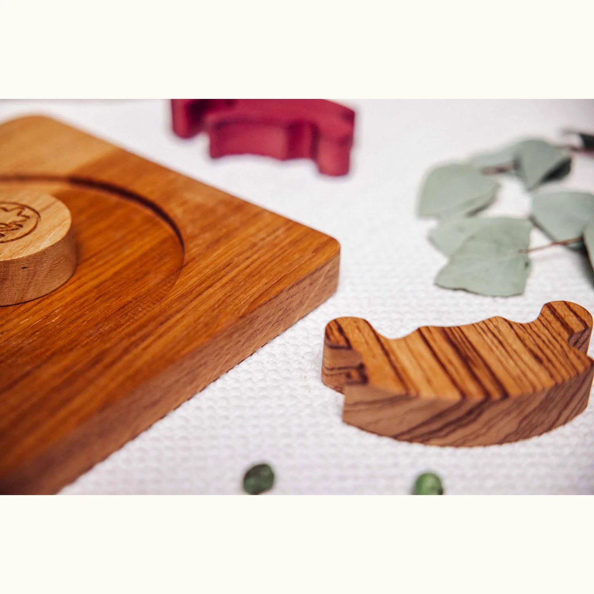 Unity Puzzle partially disassembled on linen surface, showing Oak base board, Zebrano striped curved piece, and Padauk segmen
