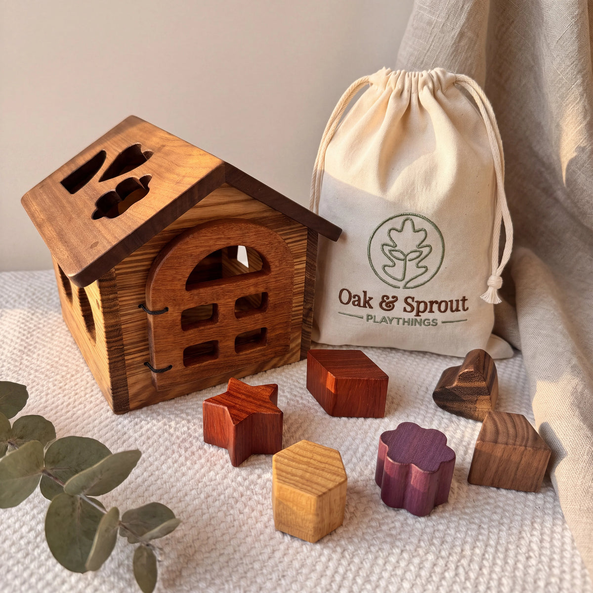 Shape Sorting House gift set with Zebrano walls, Walnut roof, and six loose hardwood blocks on cream playmat
