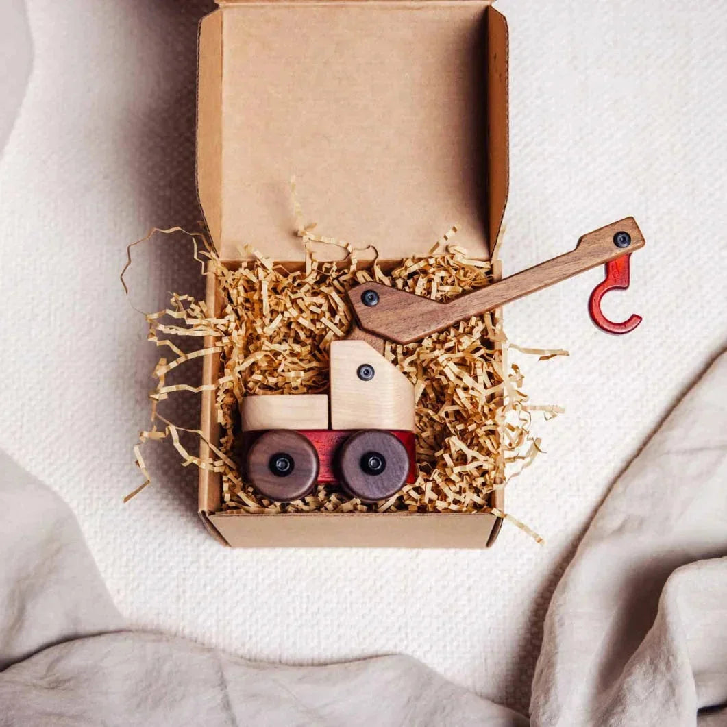 Oak & Sprout wooden crane truck in kraft gift box with shredded paper, maple cab, walnut arm, padauk hook beside box