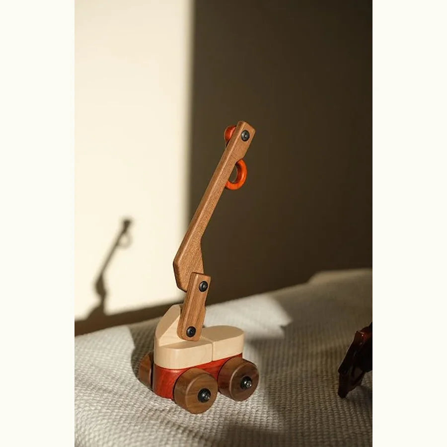 Walnut & Maple Crane toy on linen, boom raised, showing maple cab, padauk accents and walnut boom