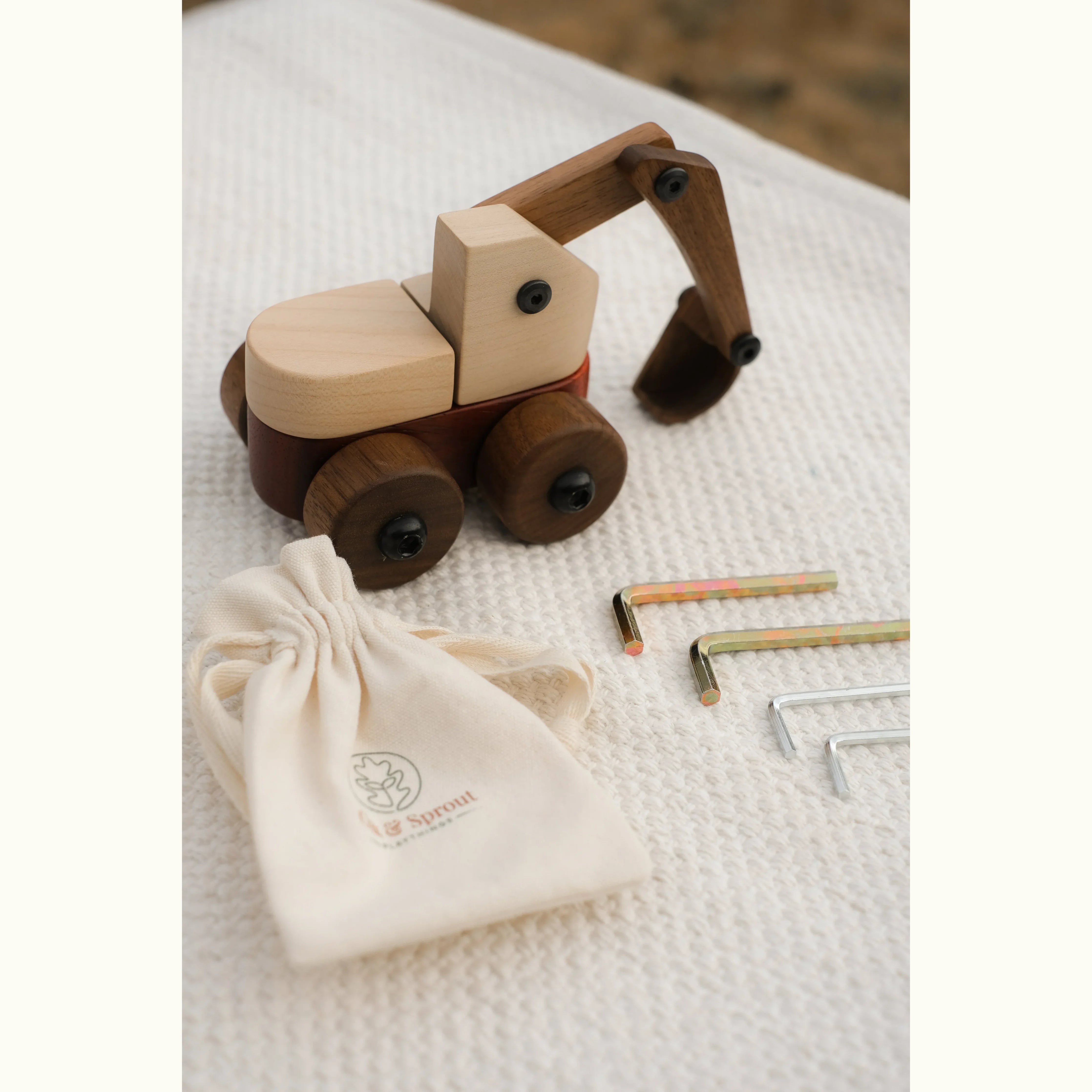 Maple Padauk Walnut excavator with Oak & Sprout muslin pouch and three hex keys on white waffle fabric