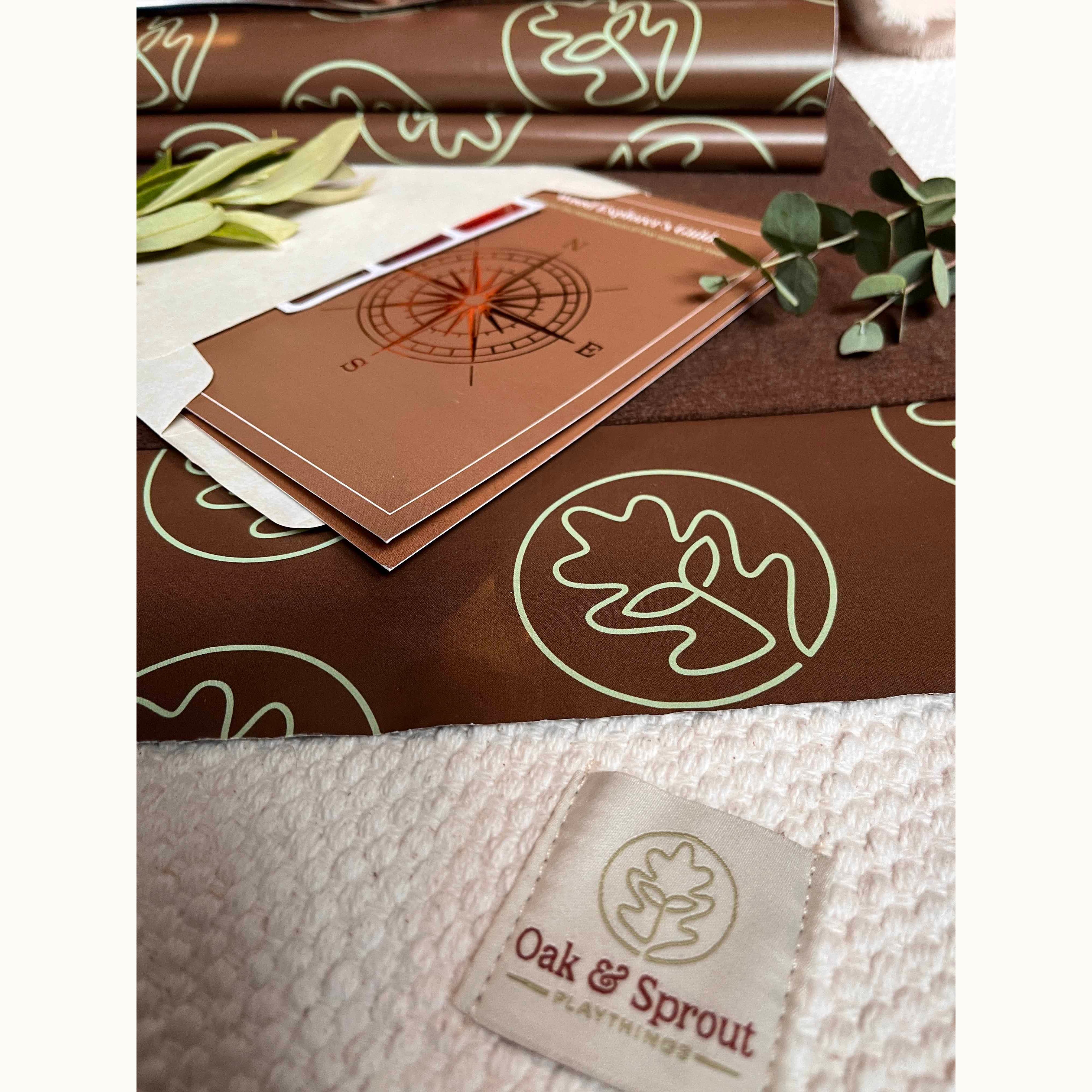 Oak & Sprout Numbers Tracing & Balls kraft packaging, sage-green leaf wrap, Explorer's Field Guide insert, and branded fabric