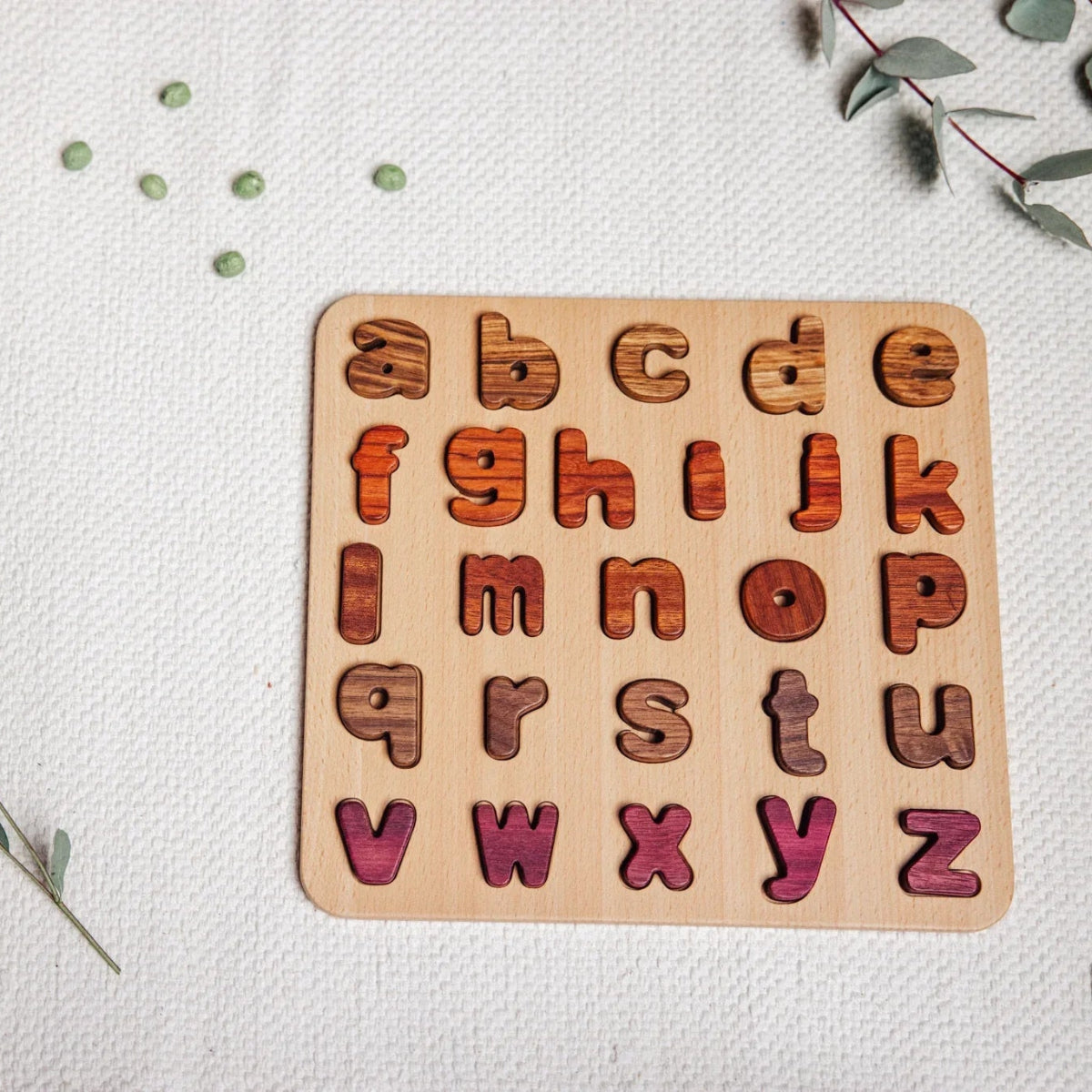Wooden alphabet puzzle on a light background with greenery