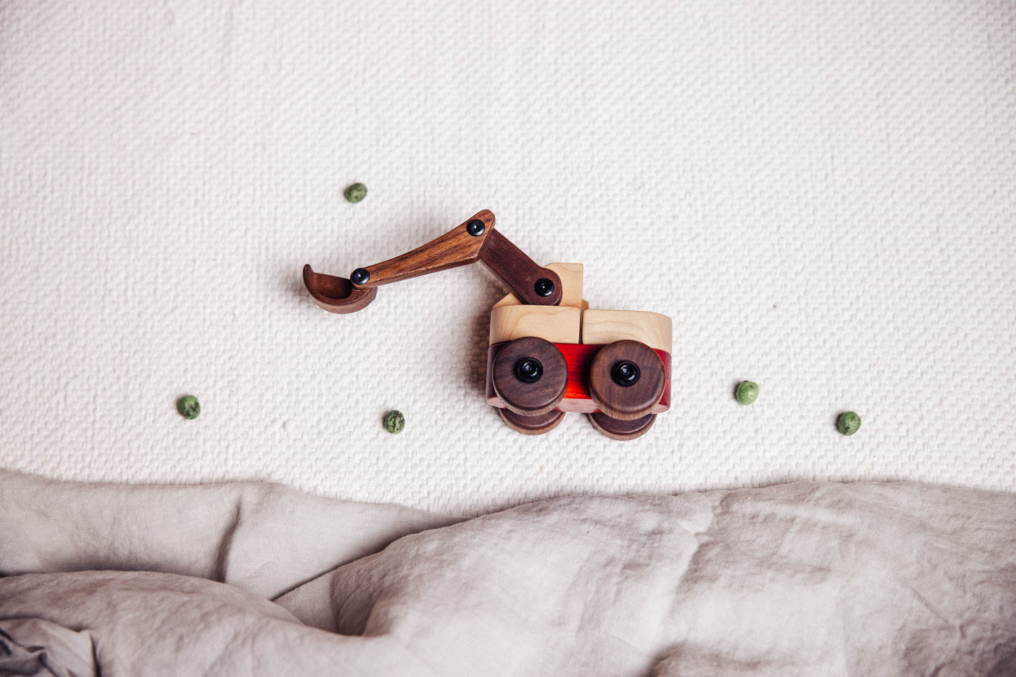 Wooden toy bulldozer on a textured surface with scattered green buttons.