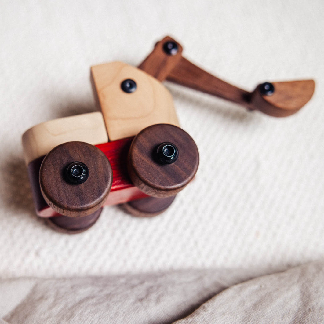 Wooden toy excavator on a textured surface