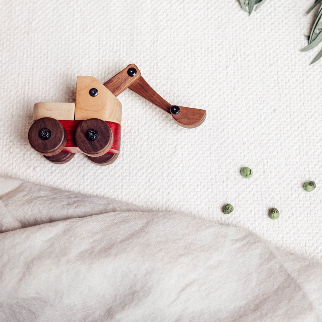Wooden toy truck on a textured surface with green leaves