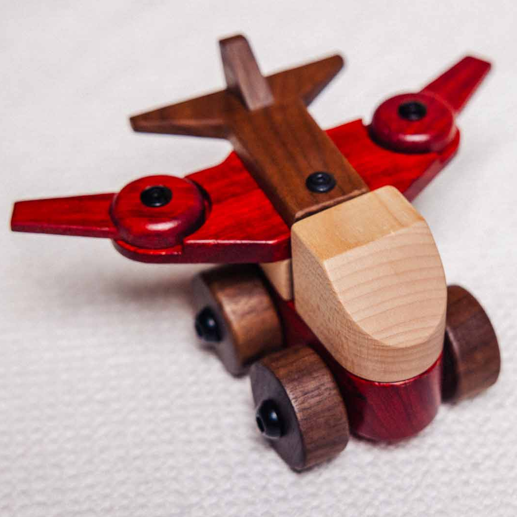 Wooden toy airplane with red and brown colors on a white background