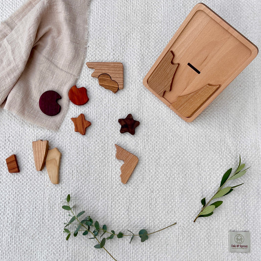 Beech shape-sorter with naturally coloured wood pieces (Padauk, Purpleheart, Zebrano) on white cotton play mat – Oak & Sprout