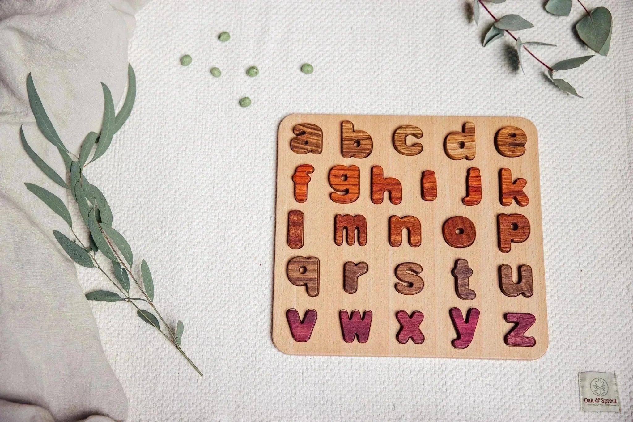 Oak & Sprout alphabet puzzle flat-lay, fully assembled, showing maple, padauk, tigerwood, walnut and purpleheart letter