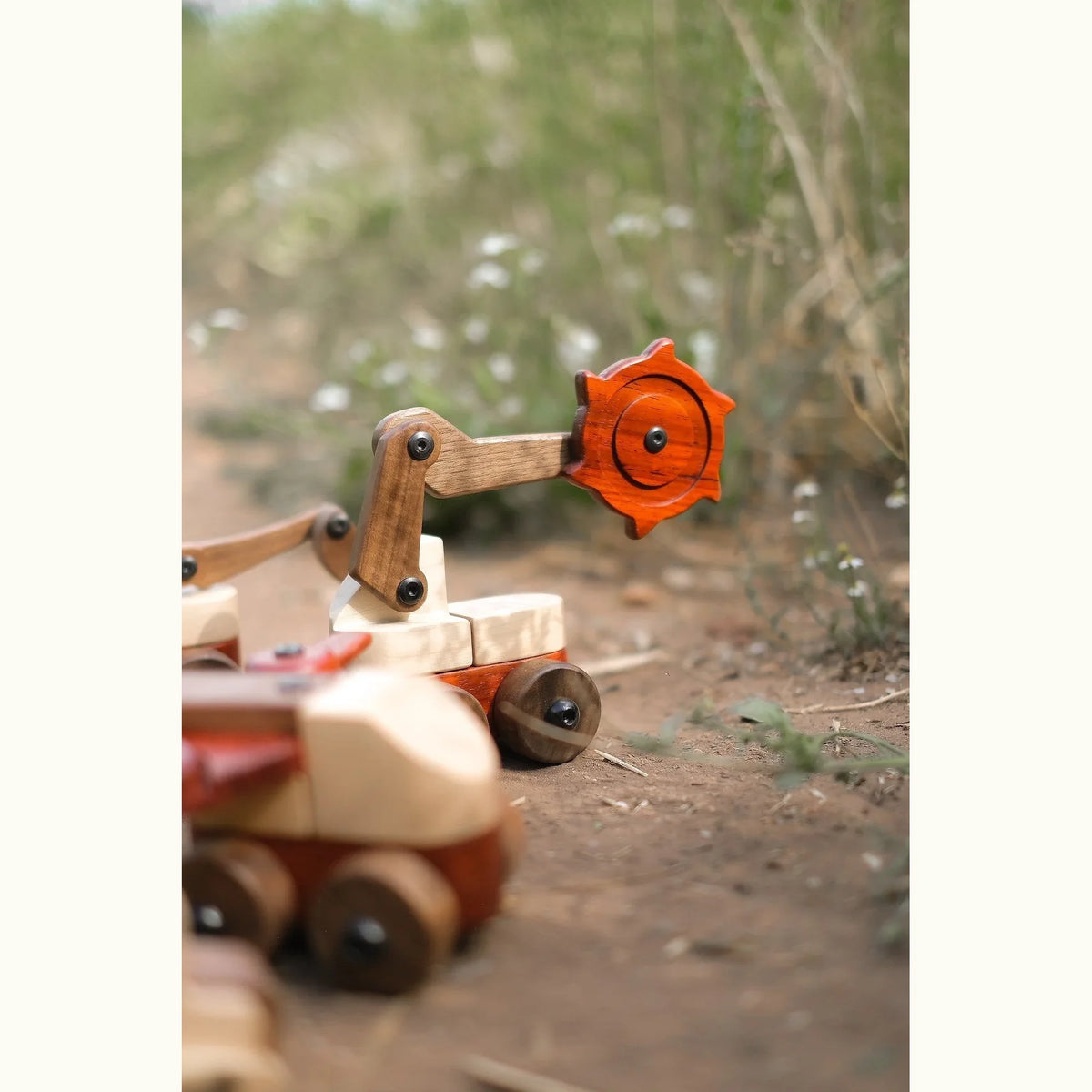 Padauk & Maple Trench Digger cutter wheel and walnut pivot arm close-up, shot at ground level on natural earth